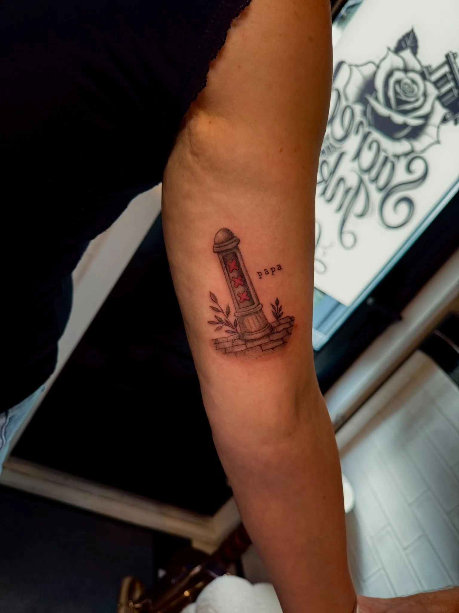 Fineline tattoo van een Amsterdammertje met takjes en het woord papa op de bovenarm
