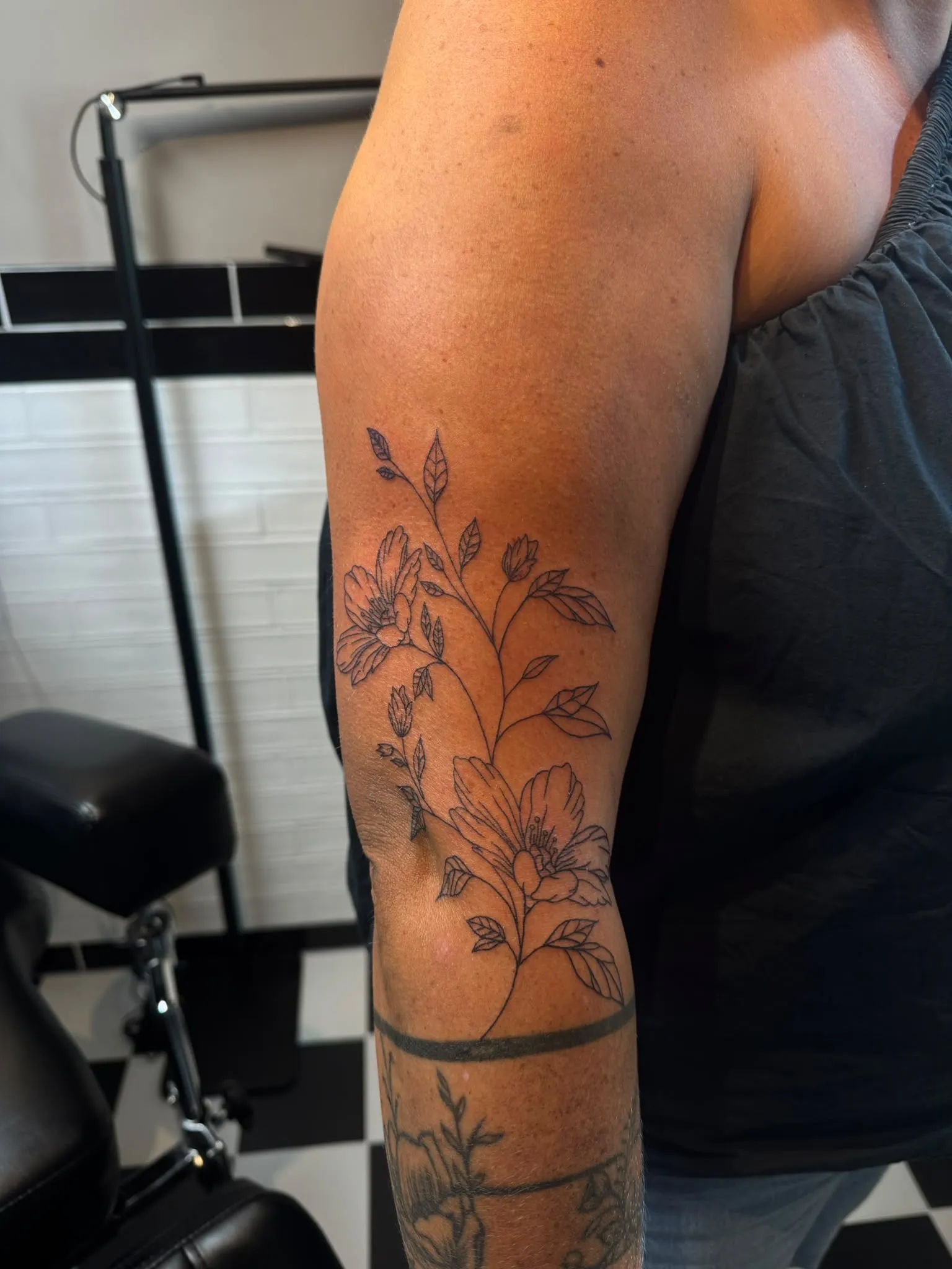 Fineline bloemen tattoo op de bovenarm