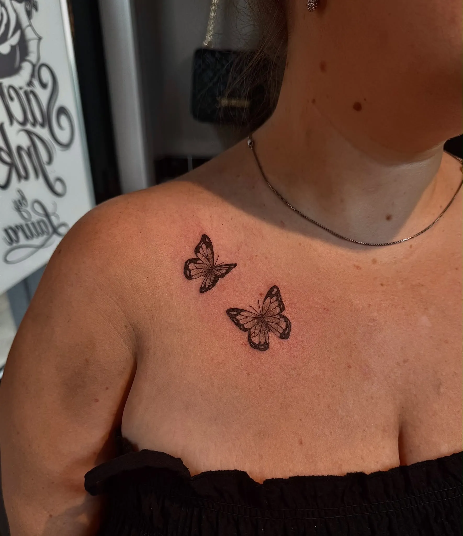 Fineline tattoo van twee vlinders bij het sleutelbeen