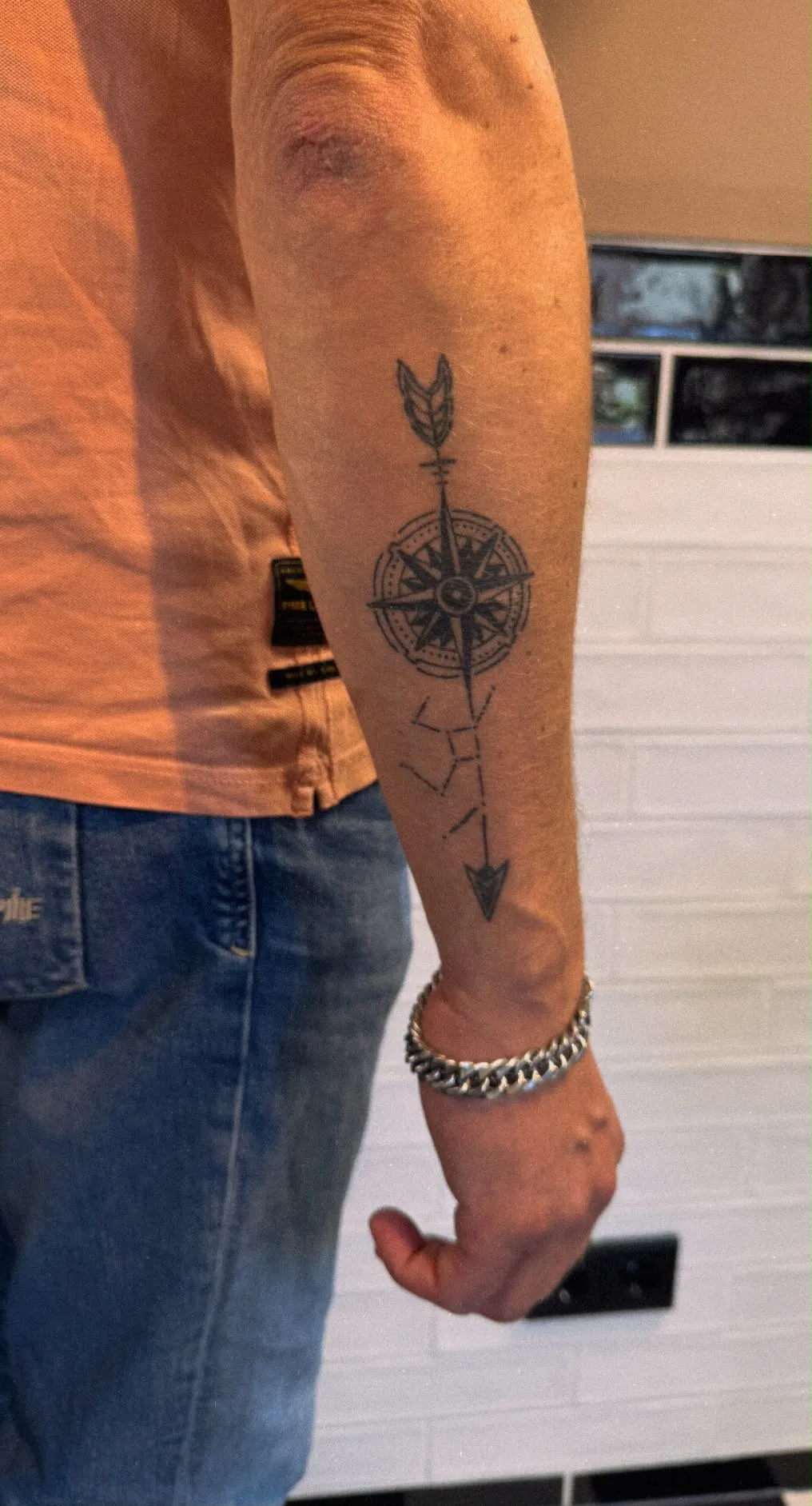 Ornamentale tattoo van een kompasroos met pijl en sterrenbeeld op de onderarm