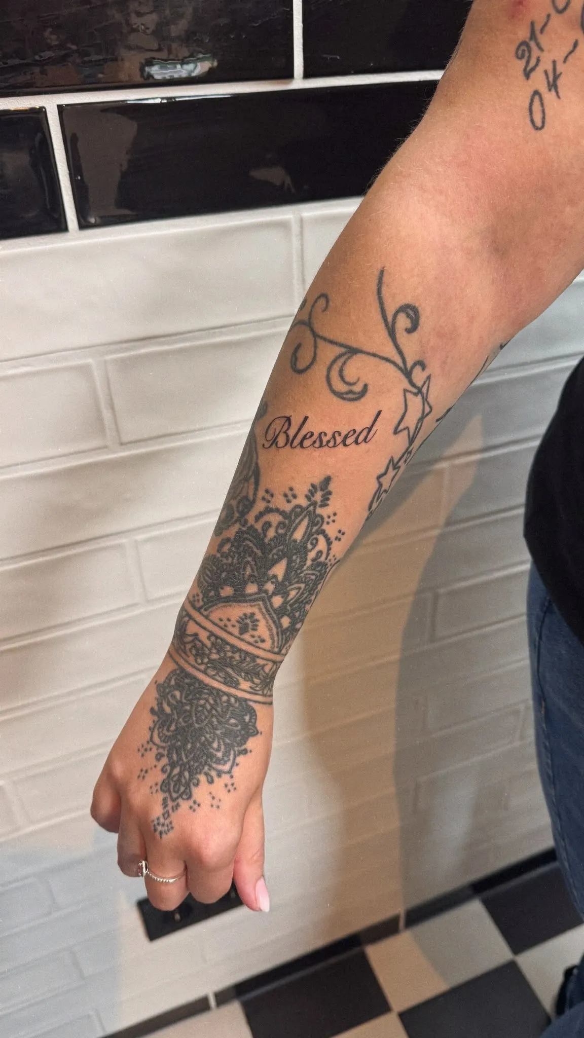 Tekst tattoo "Blessed" in script op de onderarm