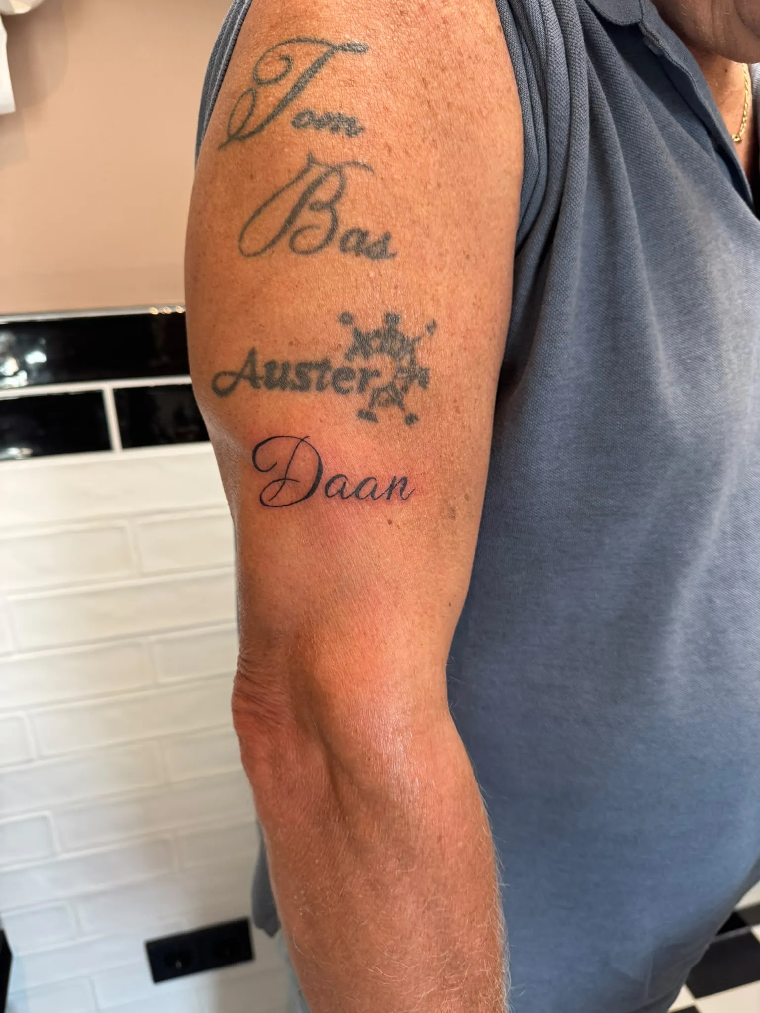 Tekst tattoo met de naam Daan in script op de bovenarm